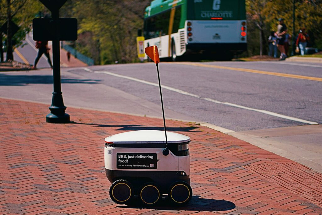 Robot pengantar otonom melintasi trotoar kampus untuk mengantarkan paket last-mile delivery