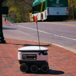 Robot pengantar otonom melintasi trotoar kampus untuk mengantarkan paket last-mile delivery